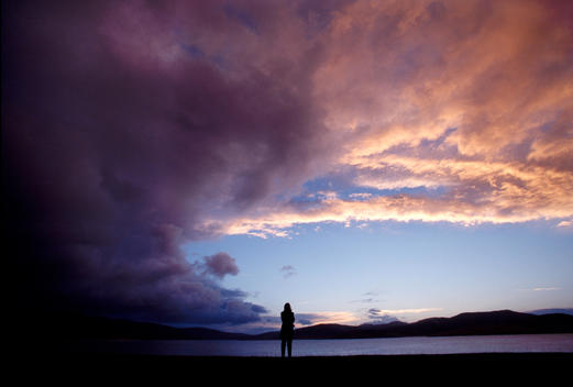 A Women Stands Alone Silhouetted Watching The Sunset As A Storm Comes In From The Southeast On The Island Of Taransay.