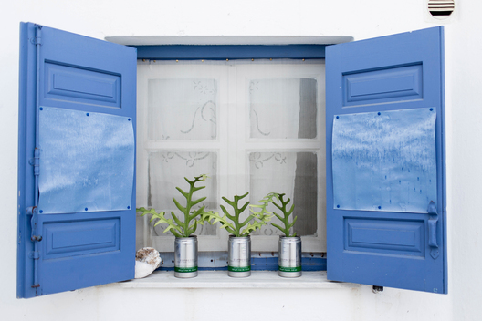 plants growing out of coffee tins in window on greek island
