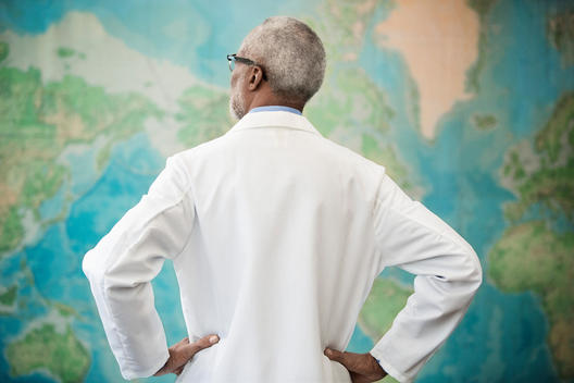 Black doctor examining world map in office