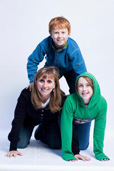 Portrait of caucasian mother, age 45-50 years old with son and daughter, ages 8-12 years old in studio making human pyramid