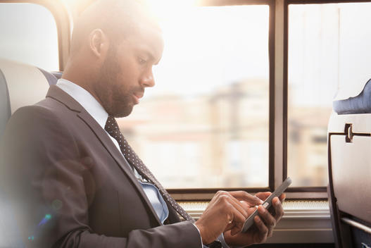 Black businessman using cell phone on subway