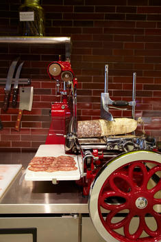 Red Vintage Meat Slicer And Knives On Counter Cutting Sausage.
