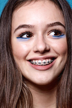 Female teenager with braces, smiling headshot looking away from camera
