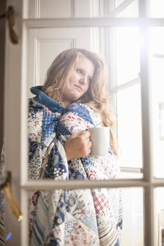 Teenage girl wrapped in a blanket holding a coffee mug