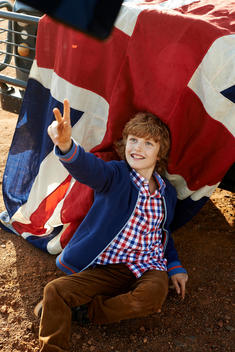 boy in front of english flag making a gesture of victory