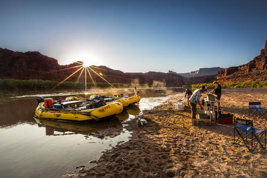 Camp and rafts on a river at sunset.