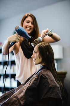 Stylist blow drying client\'s hair in salon