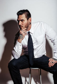 Portrait, Tattooed man with beard, wearing a white dress shirt and black tie.