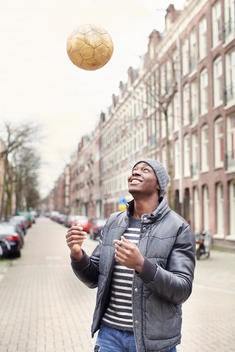 Young man on street throwing soccer ball, Amsterdam, Netherlands