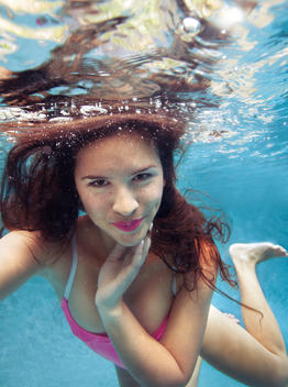 close up of woman with dark hair and freckles smiling underwater