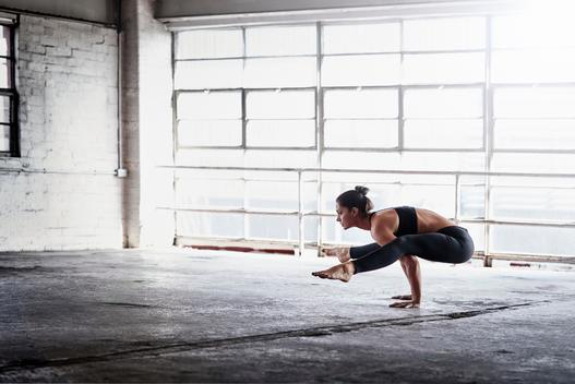 Woman practicing yoga in front of warehouse window