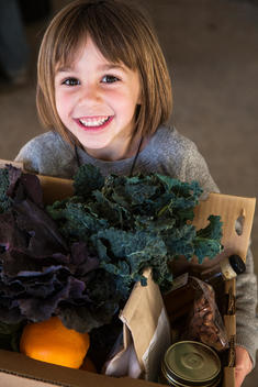 Child smiling holding box of food