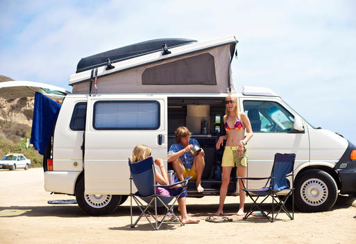 Three people hang out next to their camping van at Surf Beach, San Onofre, California