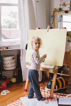 Toddler drawing on easel in bedroom