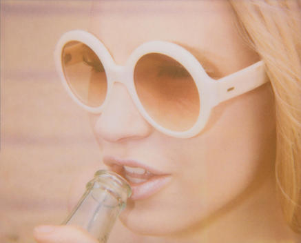 Retro 1970s blonde beach bunny sipping from a vintage coke bottle