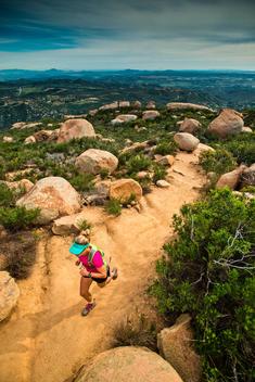 A girl in athletic wear runs up the Mt. Woodsen Trail outside of San Diego, CA.