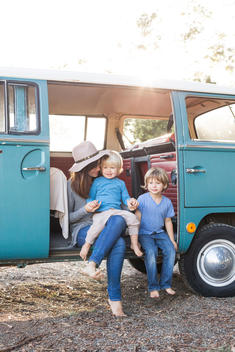 30 something mom with straw hat and 2 and 5 year old boys sitting in vintage van.