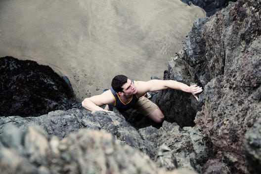An athletic man rock climbing at the beach