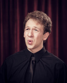 Male choir singer in front of red stage curtain singing