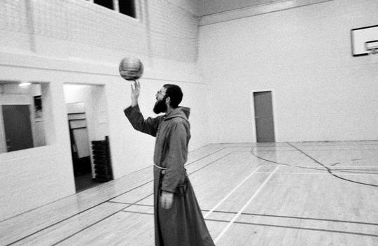 American Monk Dressed In His Habit Demonstrates How To Spin A Basketball On The Finger Tip During A Session Of The St. Francis Basketball Club.