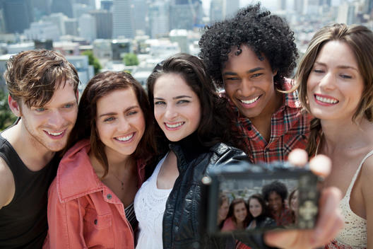 A group of five twenty year olds crowd in to take a selfie overlooking San Francisco.