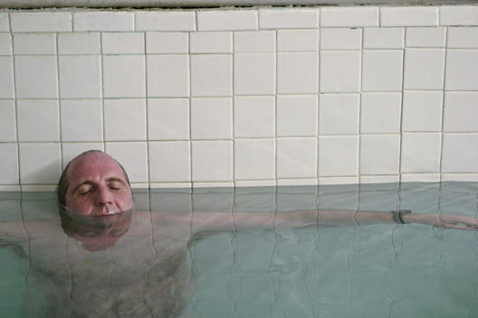 A Man Floating In Water At A Bath House.