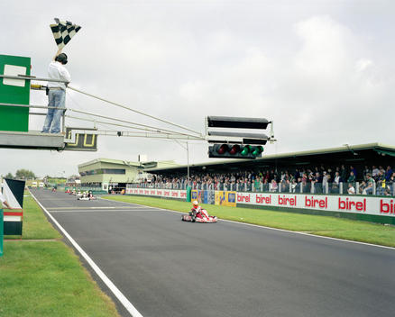 A Driver Sees The Checkered Flag To Be The First Past The Finishing Line For Victory In The Msa British Short Circuit Kartmasters Grand Prix, While Watched By Spectators In The Stand.