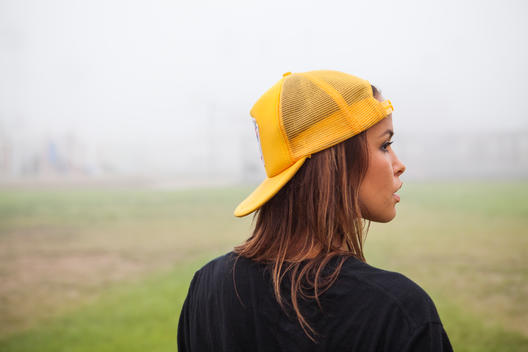 Girl in yellow hat looks to the right in the fog.