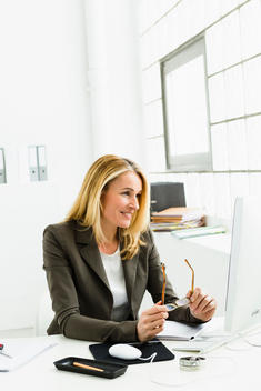 Germany, Businesswoman looking at computer, smiling