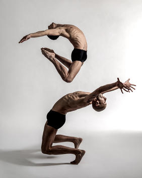 White male dancers in duo jazz jump against a white background