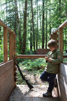 a young boy filling a rifle magazine with bullets at a shooting range in the woods at Clayoquot Wilderness Resort
