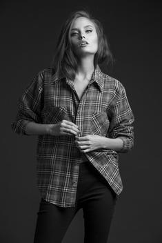 Fashion model buttoning shirt in studio in black and white.