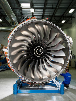 A worker kneels down next to an aircraft engine inside the Boeing factory