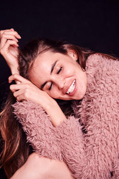 Brunette woman in pink fur coat smiling