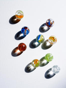 Group Of Multi Colored Marbles Casting Shadows.