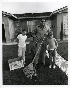 A family poses in front of a common minimal suburban home
