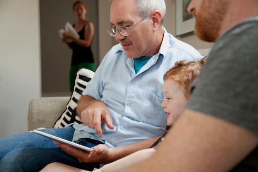 Boy looking at digital tablet with father and grandfather