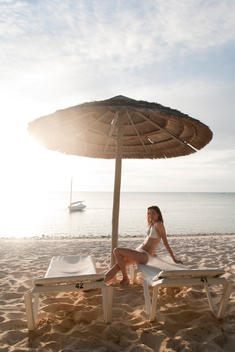 Woman In Bathing Suit Sitting On Dech Chairs On Beach