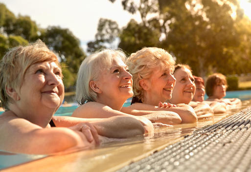 Older Caucasian women leaning on edge of swimming pool
