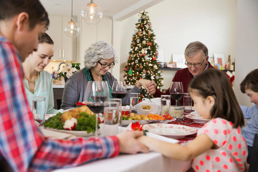 Multi-generation family saying grace before Christmas dinner