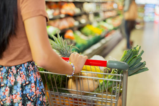 Close up of woman pushing full shopping cart in grocery store