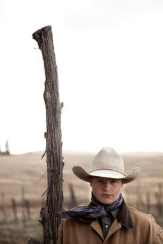 Young cowboy portrait with fencepost