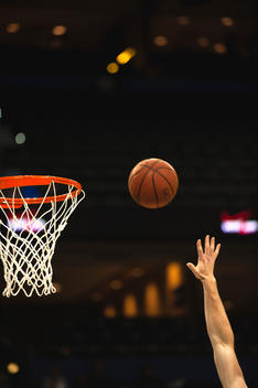 Basketball player throwing ball toward basketball hoop, cropped