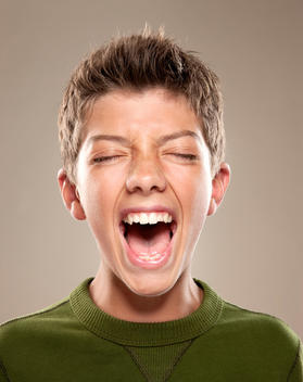 Portrait of an adolescent male yelling, eyes closed