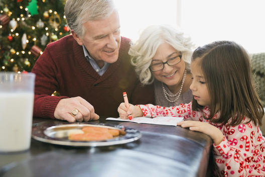 Grandparents helping girl write letter to Santa Claus