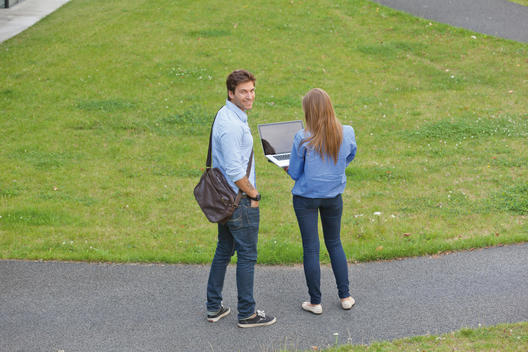 Germany, North Rhine Westphalia, Duesseldorf, Young man and young woman standing on path with laptop