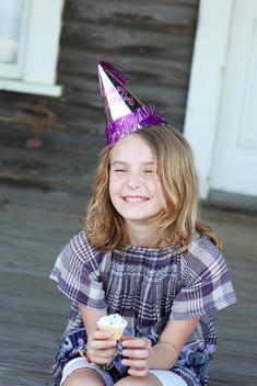 girl smiling with cup cake and birthday hat