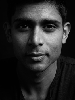 Black background portrait of late 20?s Indian male.