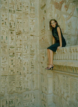 Fashion Model Sitting On Wall In Ancient Temple