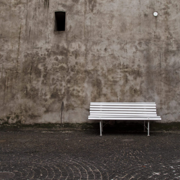 Empty white bench in front of the old wall